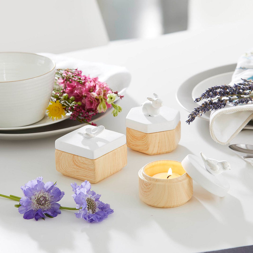Spring Pals Tealight Candle Holder Trio wooden bases with white lids with either, a rabbit, butterfly and a bird on a white table setting.
