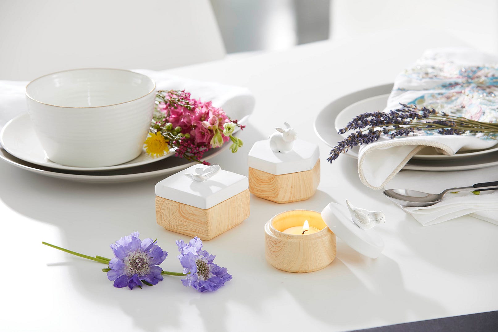 Spring Pals Tealight Candle Holder Trio wooden bases with white lids with either, a rabbit, butterfly and a bird on a white table setting.