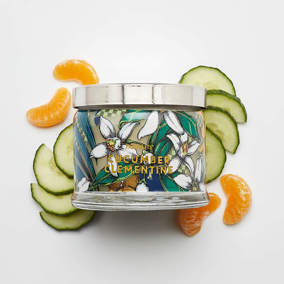 Cucumber Clementine 3-Wick Jar Candle surround b y slices of cucumber and oranges against a white background.