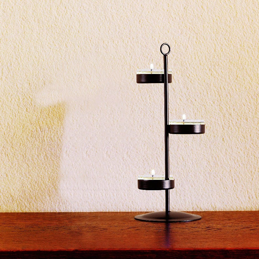 Bronze-toneTealight tree, shown with lit tealights on a wooden surface against a light backgrtound.