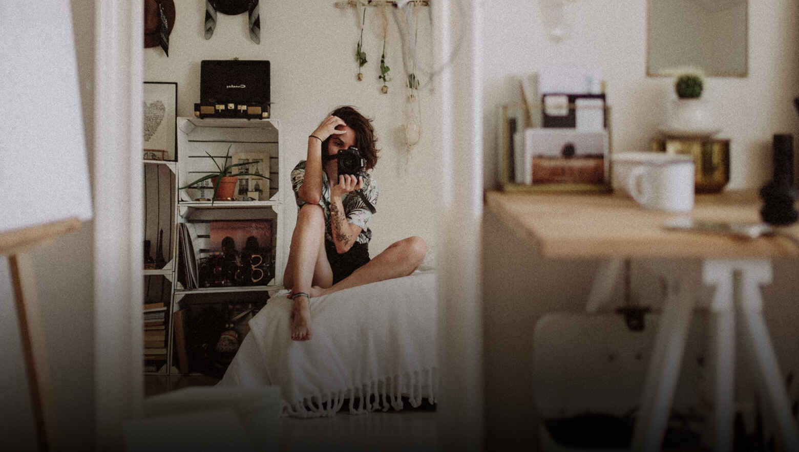 Person on chair with camera in a room with table and coffee mug.