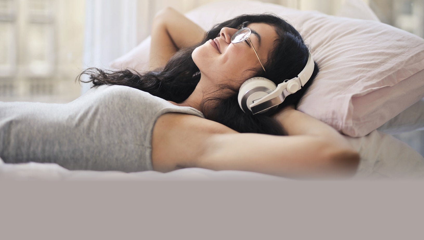 a woman lying on a bed relaxing with headphones.