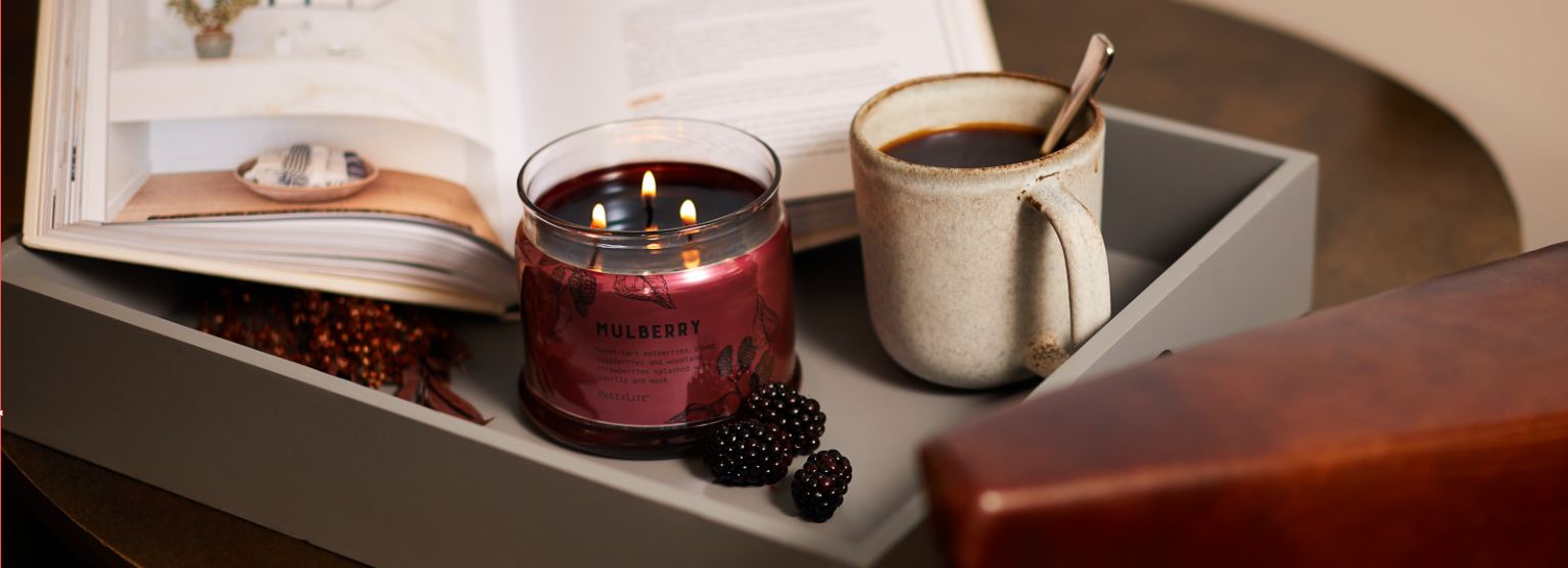 dark brown 3-wick cancel on tray with book and beverage.