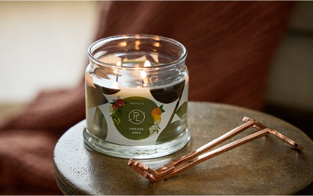 Lakeside Moss 3-Wick Candle lit with a candle snuffer