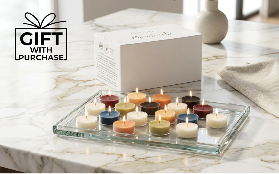 Various colored lit tealights on a glass tray on a kitchen worktop with the words "Gift with Purchase"