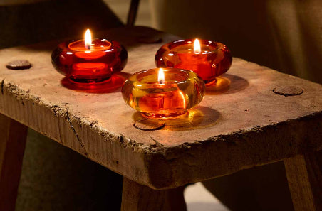 Lit Golden Honey Trio tealight holders on a wooden stool 