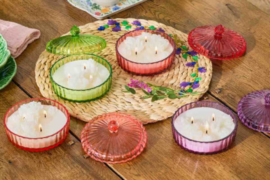 Collection of Garden Beauty Specialty Jar candles with lids on a woven mat on a wooden surface