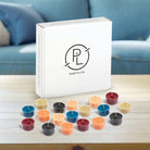 50-piece Tealight Sampler, colorful tealights on wooden table with the tealight packaging.