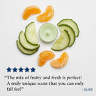 Sliced cucumbers and oranges on a white background with a tealight candle, featuring a product review quote.