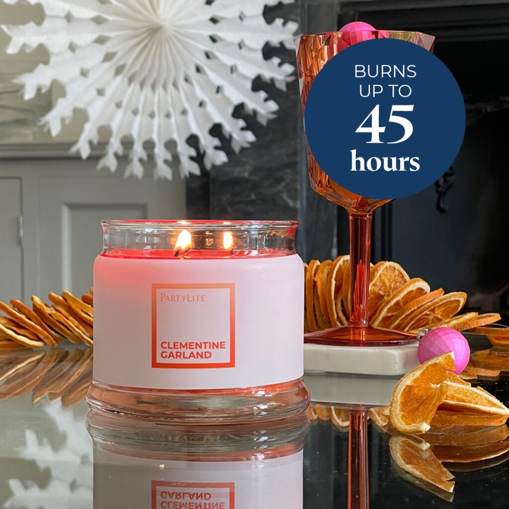 Clementine Garland 3-wick jar candle lit with decorative elements and text indicating burn time.