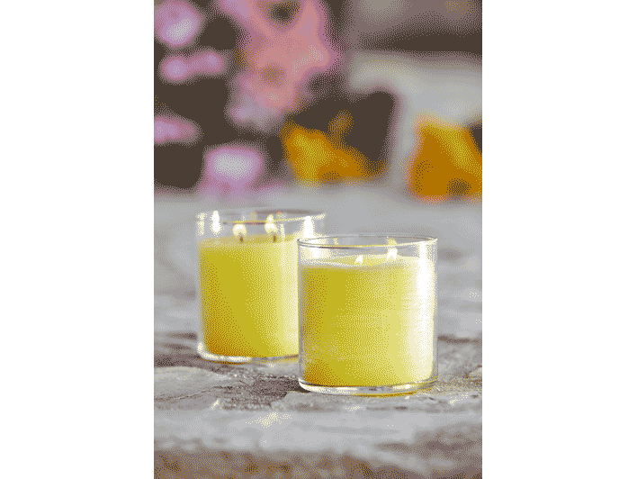 Pair of Wild Lemongrass Citronella GloLite jar candle in a yellow color against a blurred background.