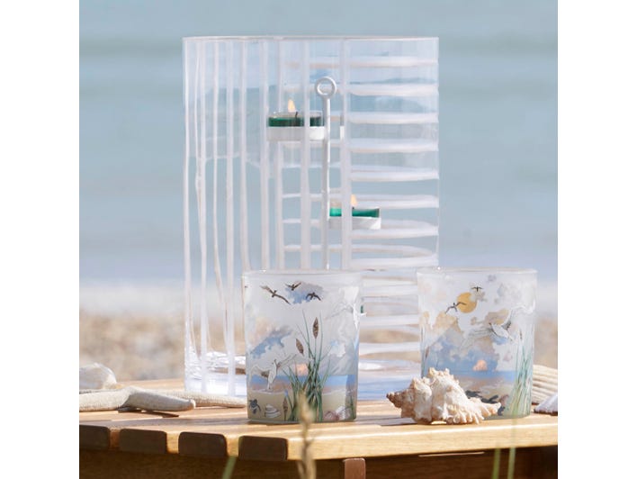 Linear Lines Glass Hurricane Candle Holder with lit tealights shown with tealight holders on a wooden surface.