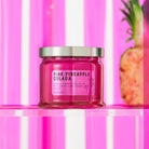 Pink Pineapple Colada 3 Wick Jar Candle against a pink and white stripy background.