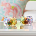  Two Rainbow Votive Candle Holders  shown with lit candles against a blurred background.