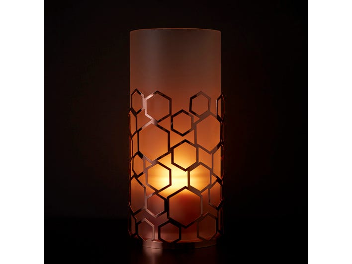 Frosted Honeycomb Hurricane with rose gold colored metal hexagon shapes with a white frosted insert, shown with a lit candle against a dark background.
