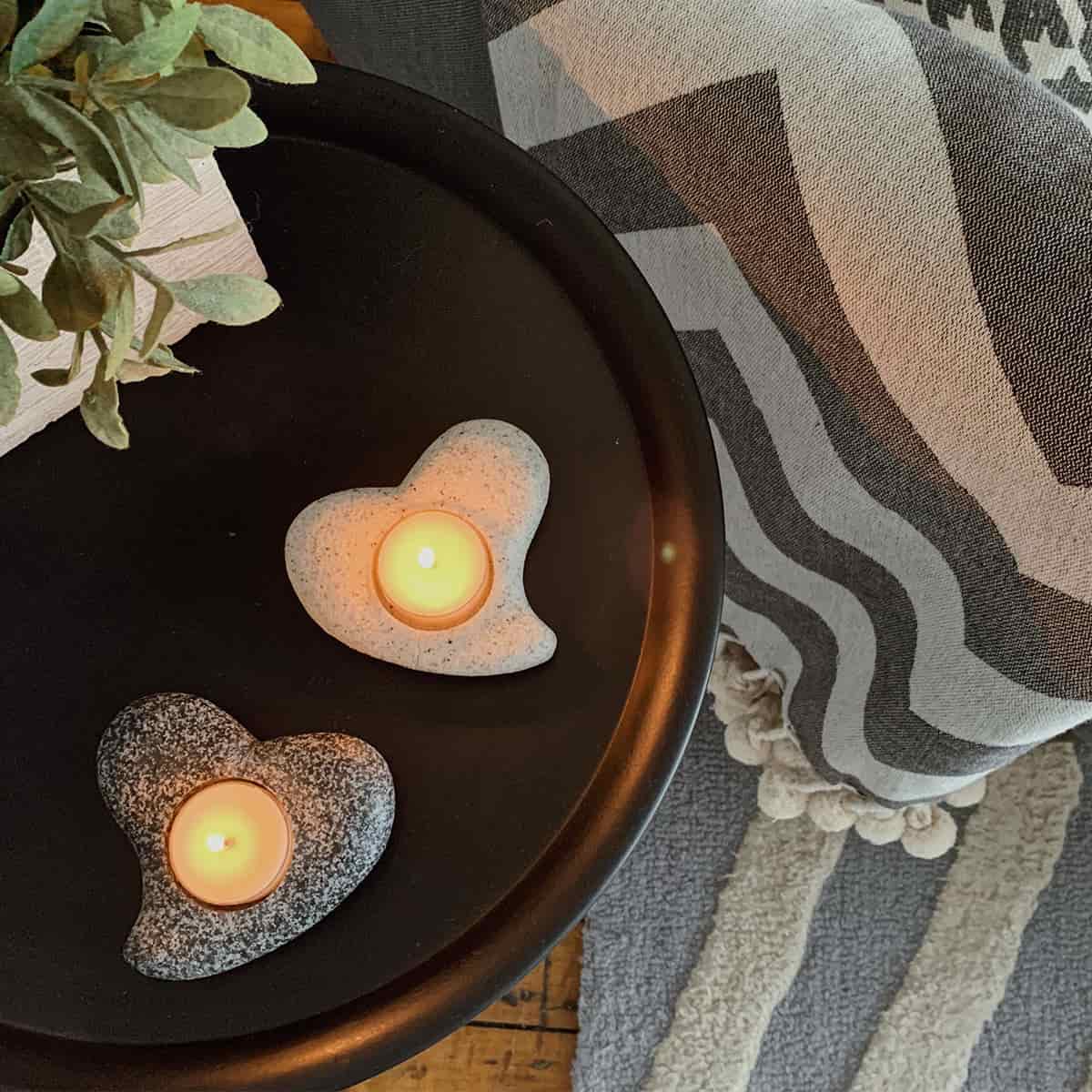 Friendship Hearts Tealight Holders with lit tealights on a drak round table with rugs on the floor.