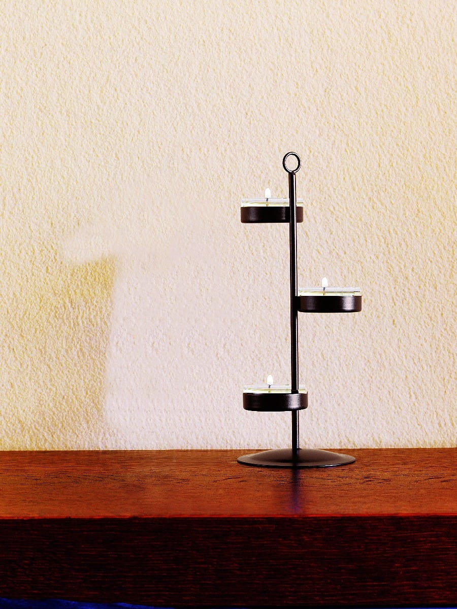  Bronze-toneTealight tree, shown with lit tealights on a wooden surface against a light backgrtound.